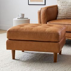 a tan leather chair and ottoman in a living room with a white rug on the floor