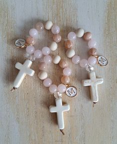 These beautiful high quality handmade mini rosaries are perfect as favors for any religious occassion  *Baptism *First Communion *Confirmation  *Wedding *Graduation Gift *Funeral memorial  *Teachers gift Each mini rosary is made using * 8mm sunstone beads *8mm rose quartz beads *8mm matte fossil jasper beads *1 8mm faceted clear glass bead *20x30mm howlite cream cross  *nylon thread *enamel with gold plate letter charm *Each mini rosary measures approx 3 inches in length.  *White organza bags are available upon request  *You can order 1 or multiple, bulk is already discounted. Don't see the quantity you need? Please message me  *Other gemstone options available  *processing time 1 to 3 days  *Arrives to US within 5 to 7 business days.  *Within Canada 7 to 10 business days. You can message Personalized Pink Rosary Bracelet For Baptism, Personalized Spiritual Rosary Gift, Handmade Pink Rosary For First Communion, Pink Jewelry For Easter Gift, Pink Cross Bracelet For Gift, Pink Cross Bracelet For Gifts, Handmade Pink Rosary For Baptism, Handmade Rosary Bracelet With Round Beads For Baptism, Handmade Pink Jewelry For Baptism