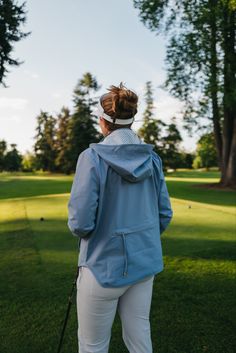 a woman standing on top of a lush green field holding a golf racquet