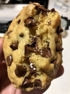 a person holding up a chocolate chip cookie