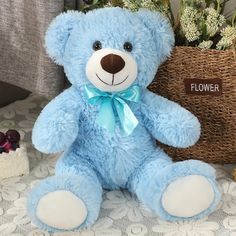 a blue teddy bear sitting next to a basket with flowers