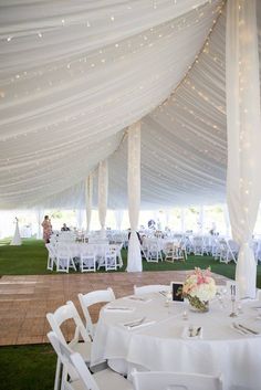 the inside of a tent with tables and chairs set up for a wedding reception in white linens