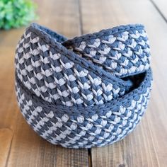 a gray and white basket sitting on top of a wooden table