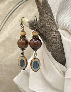 Handmade, unique boho style ceramic earrings. Brown, tan and blue in color. A nice size length at 2-1/8 inches long by .50 inch wide. The round, brown bead is glazed ceramic with a complimenting Czech glass bead at the top. From the bottom hangs a kiwi style Picasso Czech glass bead in blue and tan with a brown Picasso edge. Paired with bronze wires, hooks, and accent beads, these make a perfect casual, rustic style for everyday. They would be great for fall with a sweater and jeans. Give them a Bohemian Brown Beaded Nickel-free Earrings, Bohemian Brown Earrings As Gift, Bohemian Brown Earrings For Gift, Nickel-free Brown Bohemian Earrings, Brown Bohemian Dangle Earrings, Bohemian Brown Beaded Earrings For Gift, Nickel-free Beige Bohemian Jewelry, Bohemian Nickel-free Beige Jewelry, Brown Bohemian Earrings With Round Beads