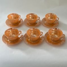 six orange glass tea cups and saucers