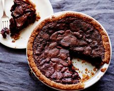 a piece of chocolate pie on a plate with a fork next to it and another slice missing