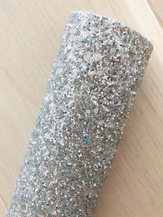 a roll of silver glitter paper sitting on top of a wooden table