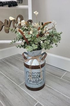 a vase filled with flowers sitting on top of a wooden floor next to a sign