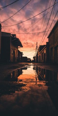 the sun is setting over an alleyway with power lines and telephone poles in the background