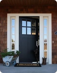 a black front door with white trim and two planters on the side of it