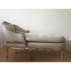 an antique style chaise lounge chair sitting on top of a hard wood floor next to a white wall