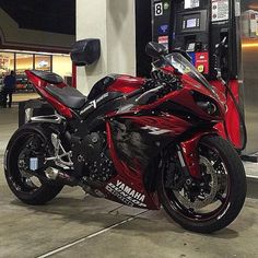 a red motorcycle parked in front of a gas pump