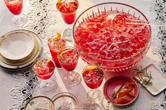 a table topped with lots of glasses filled with liquid and garnished with sprigs