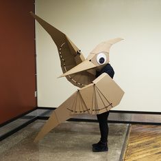 a person is standing in front of a wall with a bird made out of cardboard