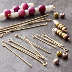 several different types of knitting needles and beads on a gray surface with one bead in the middle