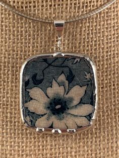 a square pendant with a flower on it