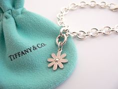 Overview: Here is a gift that she will surely adore! It is shiny, stylish, and super versatile! This piece will make someone REALLY happy! :) Offered for sale is a wonderful Tiffany & Co. Sterling Silver and Pink Enamel Daisy Charm Bracelet. Hanging from its bright Tiffany silver chain is a very pretty Pink Enamel Daisy charm! A classic Tiffany piece that any girl will adore! The Daisy charm hangs from its Sterling Silver Tiffany clasp - it is removable from the bracelet and thus allows you to w Designer Bracelets With Polished Finish For Gift, Designer Polished Finish Bracelets For Gift, Luxury Flower-shaped Bracelets As Gift, Luxury Sterling Silver Charm Bracelet Gift, Luxury Sterling Silver Charm Bracelet As A Gift, White Gold Flower Bracelet For Gift, Luxury White Gold Charm Bracelet Gift, Elegant Polished Charm Bracelet Gift, Elegant Charm Bracelet As Gift With Polished Finish