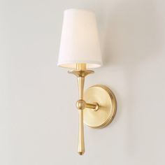 a wall light with a white shade on it's side and a gold finish