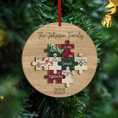 a personalized christmas ornament hanging from a tree with puzzle pieces on it