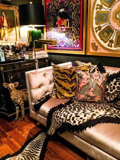 a living room filled with furniture covered in animal print pillows and blankets on top of a wooden floor