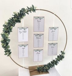 the table numbers are arranged in a circle with greenery on it and hanging from hooks