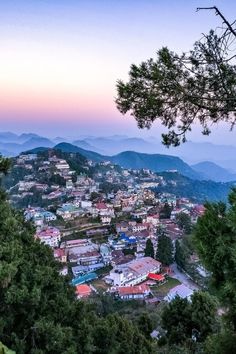 the city is surrounded by trees and mountains in the distance, as seen from above