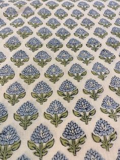 blue flowers on white fabric with green leaves in the center and small dots at the bottom