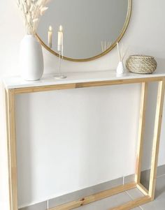 a white table with a mirror and candles on it next to a vase filled with flowers