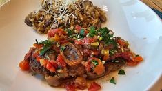 a white plate topped with meat and veggies on top of a wooden table