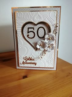 a 50th anniversary card with white flowers and a gold heart on the front that reads 50 golden anniversary