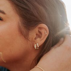 a close up of a person with ear piercings on their ears and wearing gold jewelry