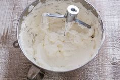 a metal bowl filled with batter on top of a wooden table