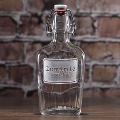 a glass bottle sitting on top of a wooden table next to a brick wall in the background