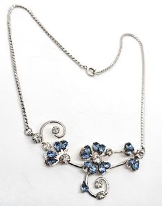 Lucky Clover pear cut blue rhinestone rhodium plated mid century vintage necklace. Good vintage condition with little to no signs of normal vintage wear. No missing or black stones. Foil behind the blue stones show small signs of aging. Rhodium plated silver toned metal with spring ring clasp. necklace measures 16.5 inches long. Vintage Blue Necklace For Evening, Vintage Blue Necklace For Anniversary, Vintage Silver Rhinestone Pendant Necklace, Black Stones, Blue Stones, Clasp Necklace, Lucky Clover, Mid Century Vintage, Small Signs