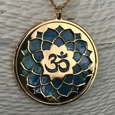 "Om in 24 carat gold on 925 silver and blue mother of pearl backdrop. Om is one of the most important spiritual symbols, a sacred sound in Indian religions, found also in some chapters of the Veda. It has variously been associated with concepts of \"cosmic sound\" that celebrates the creative powers of the Universe. Its sound is made up of three syllabes (A-U-M): wakefulness / darkness / present, dream / unconscious / past, deep sleep / future truth. In the jewel The five curves shaping the Om s Spiritual Mother Of Pearl Pendant Necklace, Spiritual Mother Of Pearl Jewelry With Gemstones, Blue Spiritual Locket Jewelry, Spiritual Blue Medallion Necklaces, Blue Medallion Necklace For Spiritual Style, Blue Medallion Spiritual Necklaces, Spiritual Gold Necklace With Mother Of Pearl, Spiritual Blue Jewelry For Festivals, Spiritual Hallmarked Necklaces