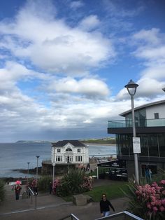 people are walking up and down the stairs to an ocean front building with pink flowers