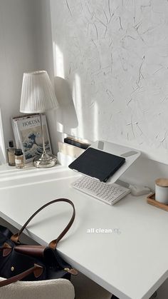 a white desk with a laptop, phone and purse on it