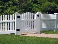 a white picket fence with black flowers on the top and bottom posts, in front of some green grass