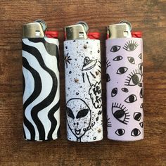 three lighters sitting on top of a wooden table next to each other with different designs