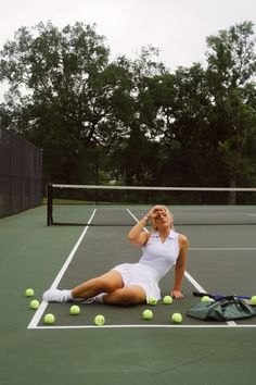 a tennis player laying on the court with her racket and balls in front of her