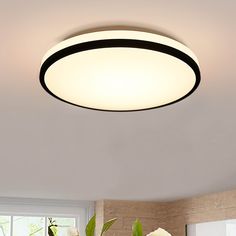 a white flower vase sitting on top of a table next to a light fixture in a room