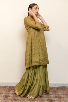 Sage green kurta with embroidered floral and half moon motifs and side gathers. Comes with an inner and matching gharara.
Components: 3
Pattern: Embroidered
Type Of Work: Thread, Sequin
Neckline: Round
Sleeve Type: Three quarter
Fabric: Kurta: Chanderi Tissue, Gharara: Cotton Silk, Lining: Cotton
Color: Green
Other Details: 
Straight silhouette
Note: Dupatta worn by the model is not for sale
Occasion: Sangeet,Mehendi and Haldi - Aza Fashions Slub Silk Sharara With Dabka And Straight Kurta, Pista Green Long Sleeve Sharara For Navratri, Navratri Pista Green Long Sleeve Sharara, Green Raw Silk Sharara, Green Cotton Silk Sharara With Straight Kurta, Pista Green Chanderi Sharara With Long Sleeves, Green Long Sleeve Sharara For Seasonal Transitions, Transitional Long Sleeve Green Sharara, Raw Silk Sharara For Eid