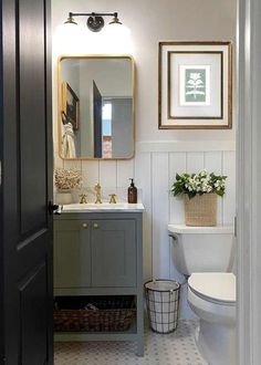 a white toilet sitting next to a sink in a bathroom under a framed mirror on the wall