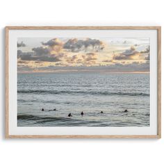 surfers in the ocean at sunset under cloudy skies framed art print by artist unknown