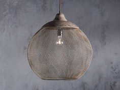 a light that is hanging from a wire on a wall with concrete walls in the background