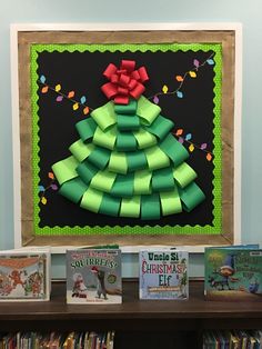 a christmas tree made out of green paper on top of a book shelf next to children's books