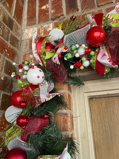 a christmas wreath on the front door with red and green ornaments hanging from it's sides