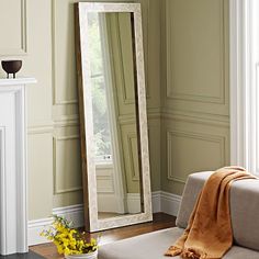 a large mirror sitting on top of a white couch in a living room next to a fire place