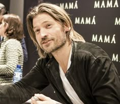 a man with long hair sitting at a table