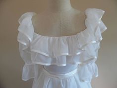 "Vintage 1990s Redux 1950s Short Sleeved; Ruffle Trimmed Wedding Gown, Dress with Full Skirt by Paris Design House, Sasson. This dress is made from a fine white organza and boasts a double satin trimmed ruffle, (top is 4 inches, bottom is 5.5 inches,) on an off-shoulder neckline. The puff sleeves are cinched part way down and have satin trim as well. It has a fitted bodice accented by a satin (attached) belt that buttons in the back with two buttons and elastic loops that have oxidized and need Vintage Victorian Dress With Ruffles For Debutante Ball, Vintage White Dress With Ruffled Skirt, White Gown With Ruffles And Fitted Bodice, Vintage White Ruffled Wedding Dress, White Regency Style Petticoat With Ruffles, Vintage Wedding Dress With Ruffled Skirt, Elegant Wedding Petticoat With Ruffles, Vintage Ruffled Dress For Debutante Ball, Vintage Gown With Ruffles For Debutante Ball